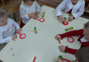 6 dzieci wykonuje kotyliony biało-czerwone przy stole